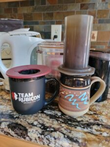 Picture of an Aeropress coffee filter and a pour over coffee filter on coffee mugs.